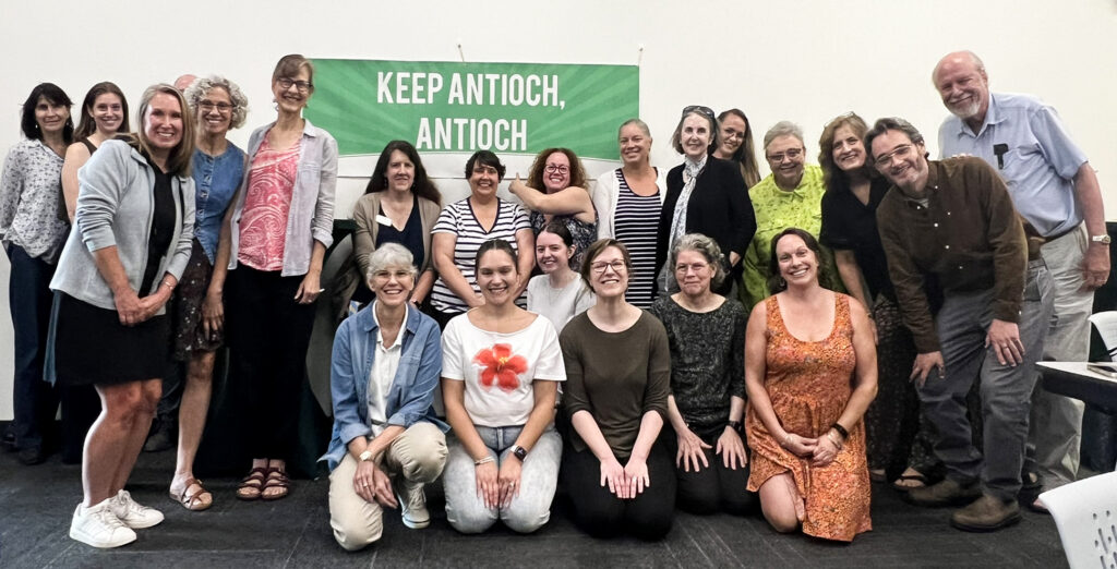 Group of Antioch community members pose together in front of a green banner reading “KEEP ANTIOCH, ANTIOCH.”